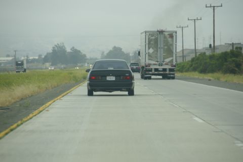 1995 Ford Taurus - A black 1995 Ford Taurus travels down a highway behind a semi-truck.