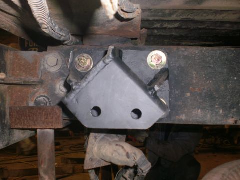 1995 Ford Bronco - Close-up of a custom shackle flip bracket attached to a vehicle's frame, showing mounting hardware and suspension components.
