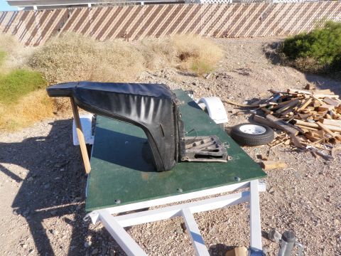 1982 Ford Bronco - Car door part on trailer with wood pile and spare tire in outdoor setting.