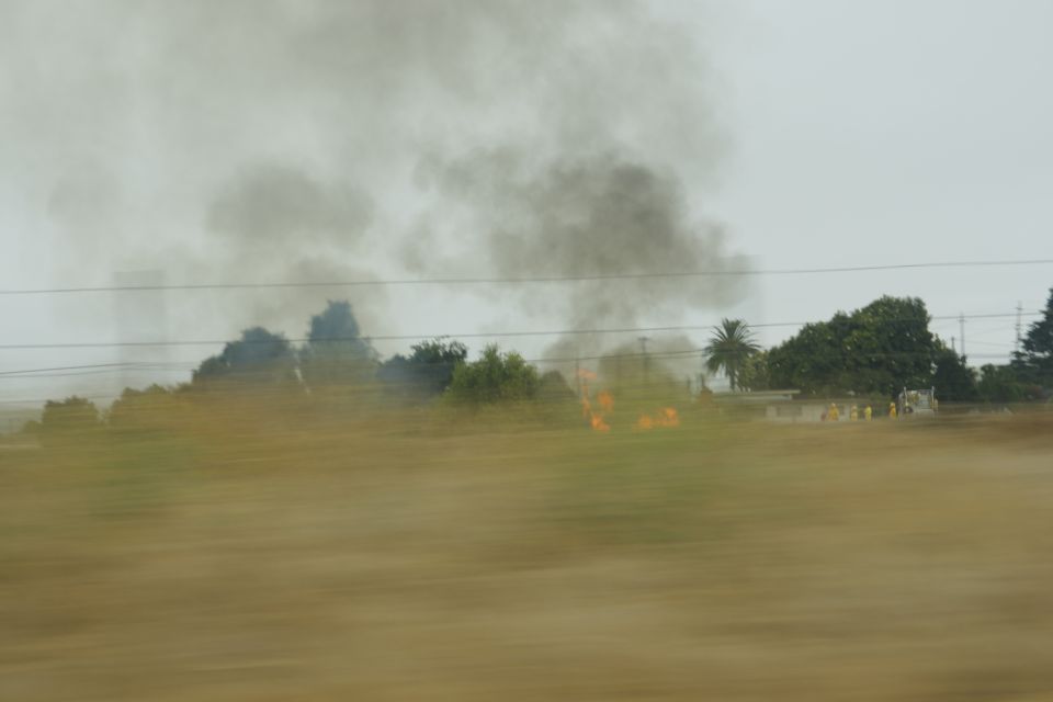 Firefighters and emergency vehicles at a scene with smoke and flames