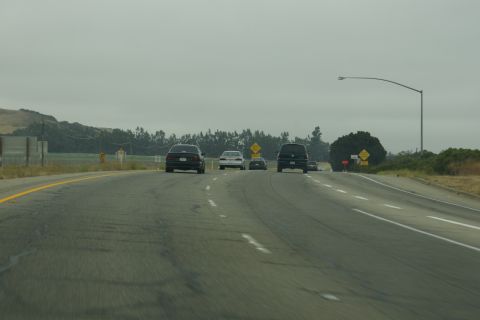 1995 Ford Taurus - Multiple vehicles travel along a multi-lane highway on a cloudy day.