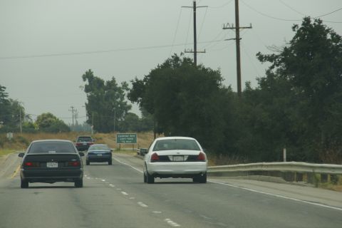 1995 Ford Taurus - White Ford Crown Victoria seen from behind on a highway with other vehicles.