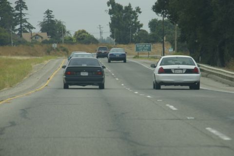 1995 Ford Taurus - Rear view of a black 1995 Ford Taurus driving on a highway with other vehicles.