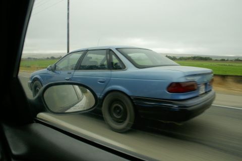 1995 Ford Taurus - Driving alongside a blue 1995 Ford Taurus on a cloudy day.