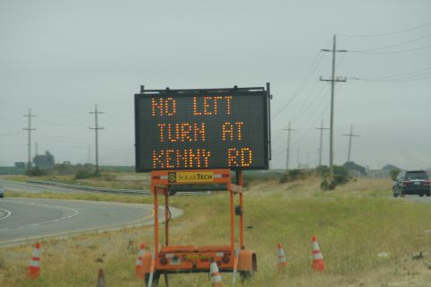 1995 Ford Taurus - A digital road sign provides traffic information on a cloudy day, with a vehicle visible in the distance.