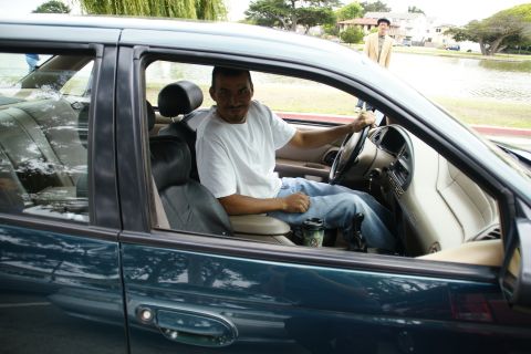 1995 Ford Taurus - A man sits in the driver's seat of a sedan, with a lake and trees visible in the background.