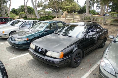 1995 Ford Taurus - Multiple Ford Tauruses are parked in a lot on a sunny day.