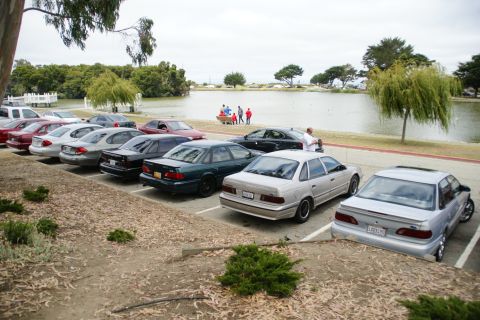 1995 Ford Taurus - A silver 1995 Ford Taurus is parked in a lot next to a lake, with other vehicles visible.