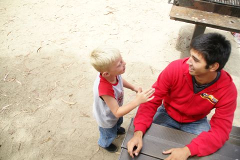 1995 Ford Taurus - A young boy interacts with a man while sitting at a picnic table outdoors.
