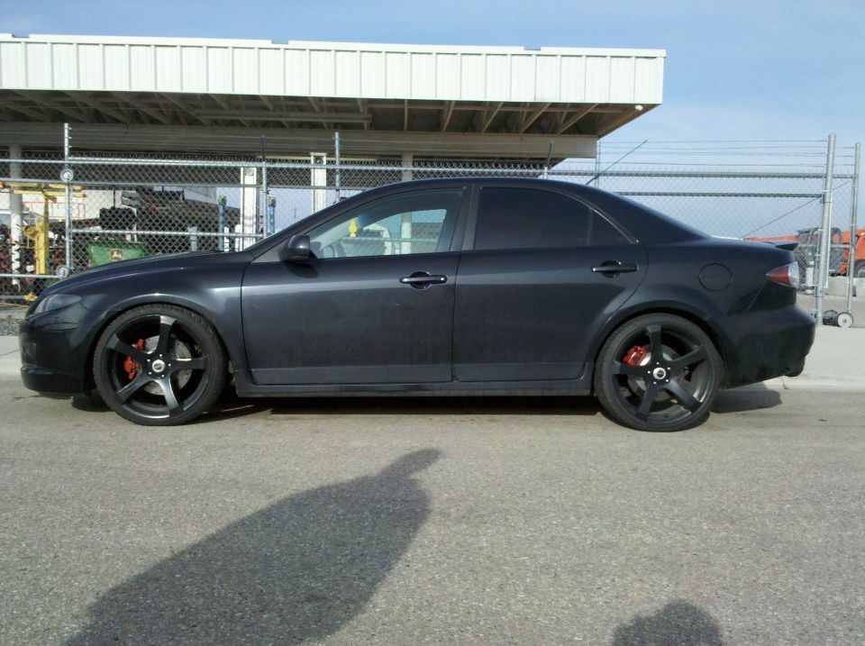 Dark sedan side view, black rims, red calipers