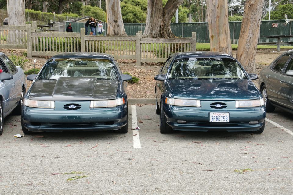 Two dark green Ford Taurus sedans parked front-facing