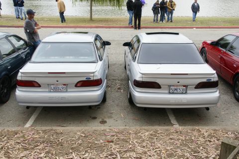 1995 Ford Taurus - Two silver 1995 Ford Taurus sedans are parked next to each other, viewed from the rear.