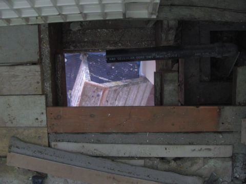 1968 Ford Mustang - Construction debris and plumbing visible through an opening in the floorboards.