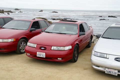 1995 Ford Taurus - Three Ford Taurus sedans parked near the ocean on a cloudy day.