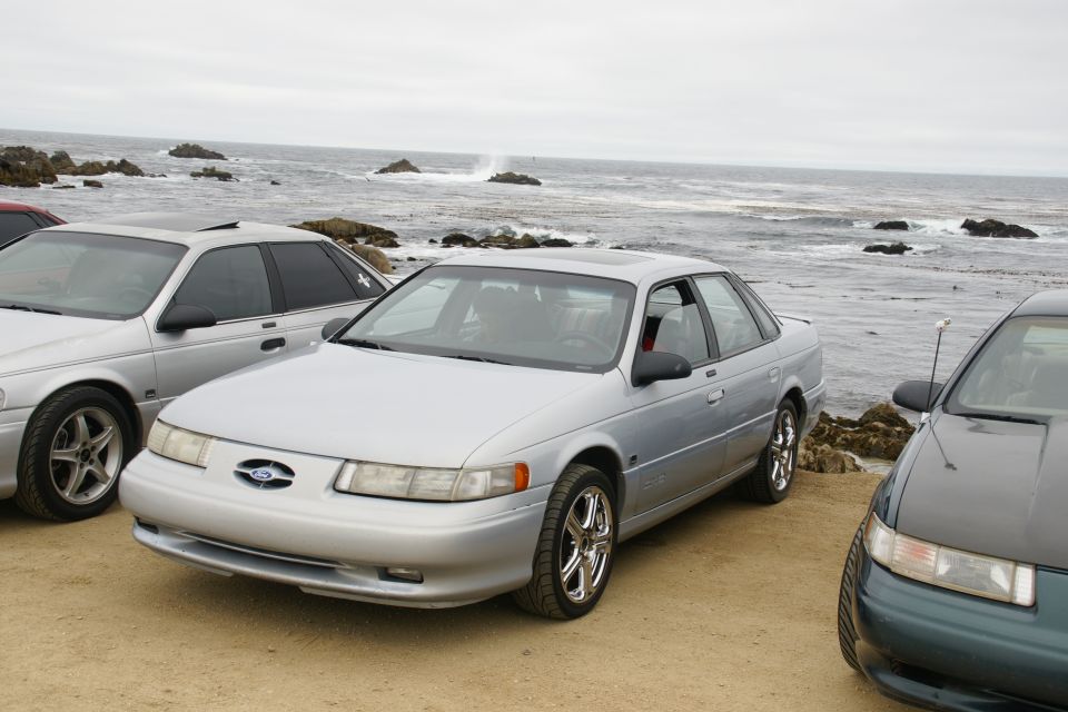 Silver sedan parked on a beach with the ocean in the background