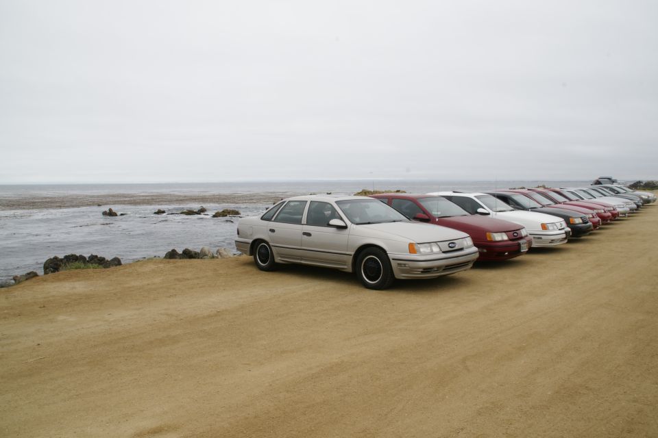 Silver sedan parked in a line of cars by the ocean