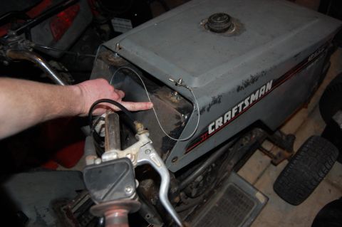 2010 Kawasaki BAYOU 220 - A hand points to the engine compartment of a Craftsman lawn tractor, possibly for repair or inspection.