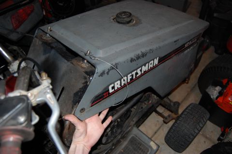 2010 Kawasaki BAYOU 220 - Close-up of a gray Craftsman riding mower hood, showing the branding and a hand near the edge.