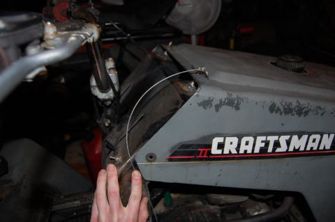 2010 Kawasaki BAYOU 220 - A hand is shown near the cable mechanism on the gray body of a Craftsman II riding mower.