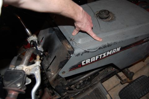 2010 Kawasaki BAYOU 220 - A hand points to the hood of a gray Craftsman lawn tractor.