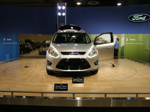 2012 Ford Crown Victoria - A silver Ford crossover SUV is displayed at an auto show with its door open and a person standing nearby.