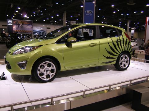 2012 Ford Crown Victoria - A green hatchback is displayed on a platform at an auto show.