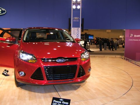 2012 Ford Crown Victoria - Red car on display at an auto show with doors open.