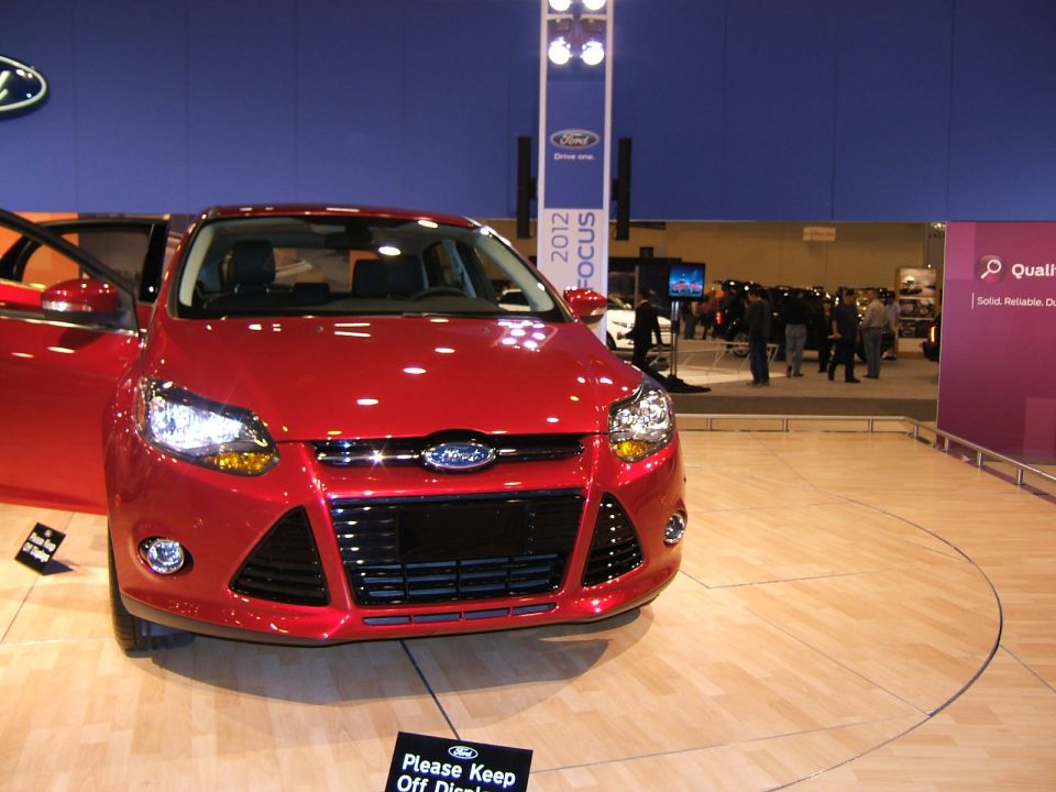 Red car with doors open at an auto show