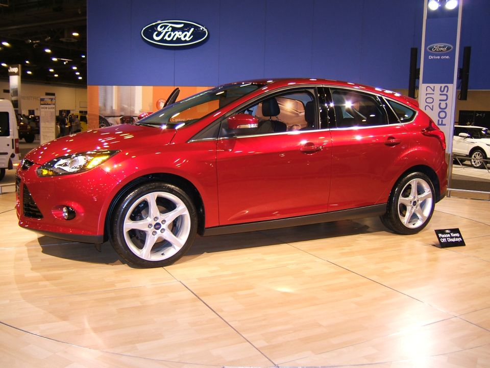 Red sedan on display indoors, possibly at a car show