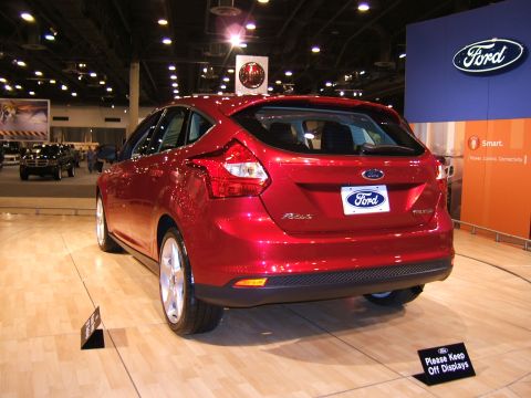 2012 Ford Crown Victoria - A red hatchback is displayed indoors with a blurred background.