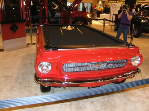 2012 Ford Crown Victoria - A unique pool table crafted from the front end of a vintage car is displayed at an auto show alongside other vehicles.