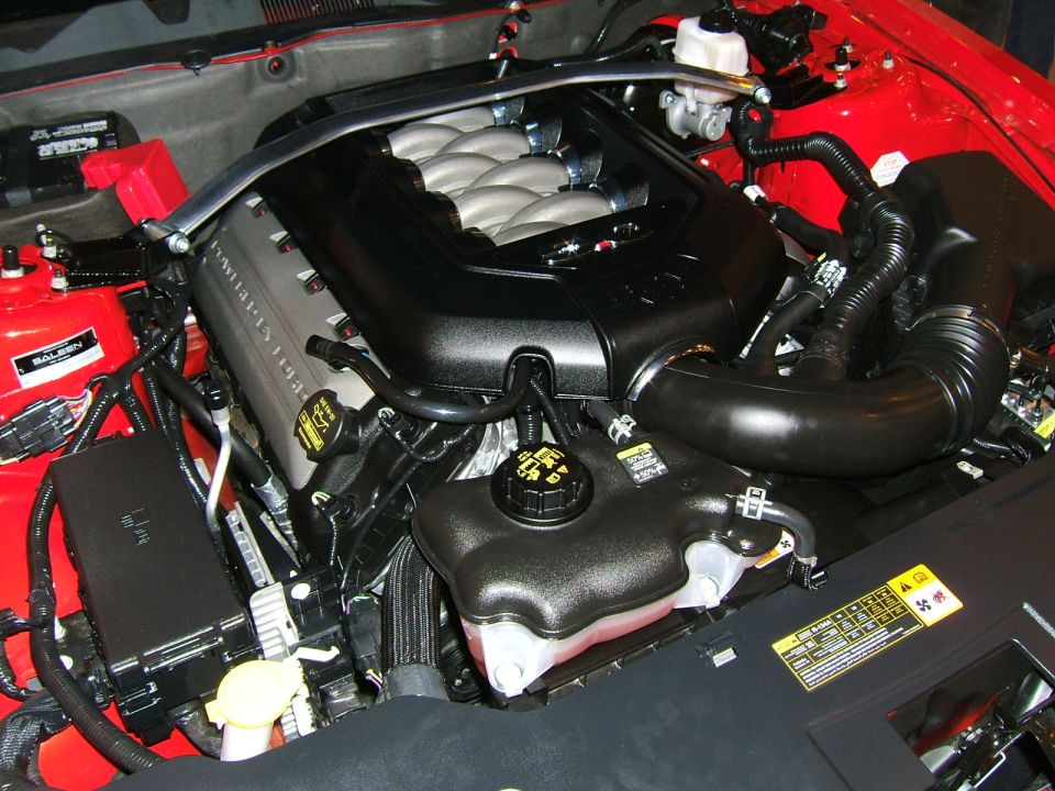 Engine bay with V8 engine components, intake manifold, and coolant reservoir visible