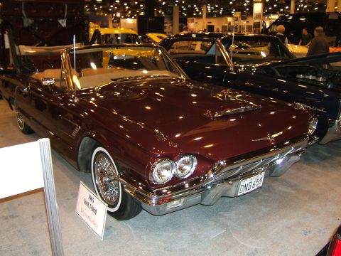 2012 Ford Crown Victoria - A classic 1965 Ford Thunderbird convertible is displayed at an auto show, with other vehicles visible in the background.