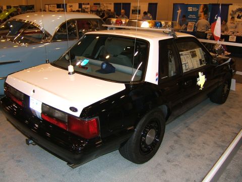 2012 Ford Crown Victoria - This police car, likely a Ford Mustang SSP, is displayed at an event next to a vintage car.