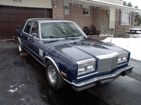 1983 Chrysler Fifth Avenue - Dark blue 1983 Chrysler Fifth Avenue sedan parked in front of a garage on a snowy day.