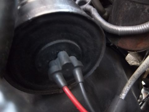 1995 Ford Bronco - Close-up of a black cylindrical component with a two-pin electrical connector attached, feeding red and black wires. Braided vacuum/wiring…
