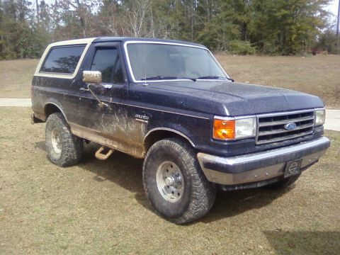 1990 Ford Bronco - This Ford Bronco is shown from the front-three-quarter angle, appearing muddy after off-road use.