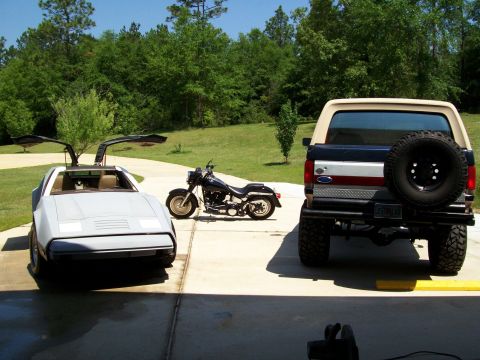 1990 Ford Bronco - A 1990 Ford Bronco is parked next to a DeLorean and a motorcycle.