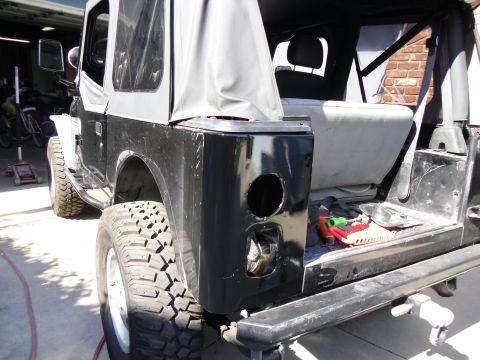1992 Jeep Wrangler - Rear view of a Jeep Wrangler TJ, missing its taillight and with tools in the cargo area.