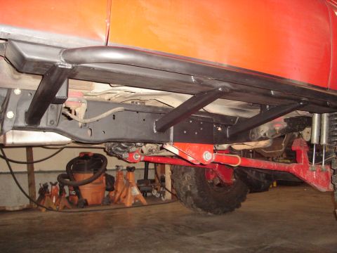 1989 Ford Bronco - Close-up view of a modified vehicle frame, showing custom rock sliders and suspension parts.