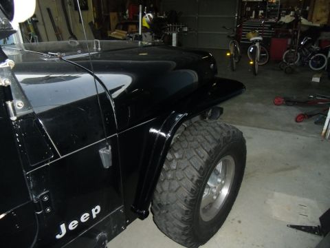 1992 Jeep Wrangler - Close-up of a black 1992 Jeep Wrangler's fender and tire, showing its off-road capabilities.
