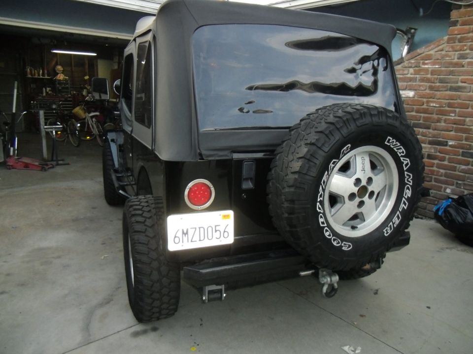 Rear view of a black Jeep Wrangler with a spare tire mounted on the back. License plate reads 6MZD056