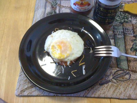 1968 Ford Mustang - A close-up of a fried egg served on a plate with cheese, accompanied by hot sauce and pepper shakers.