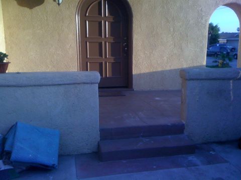 1968 Ford Mustang - A view of a house's entrance, a brown arched door and textured walls, with a car visible in the background.