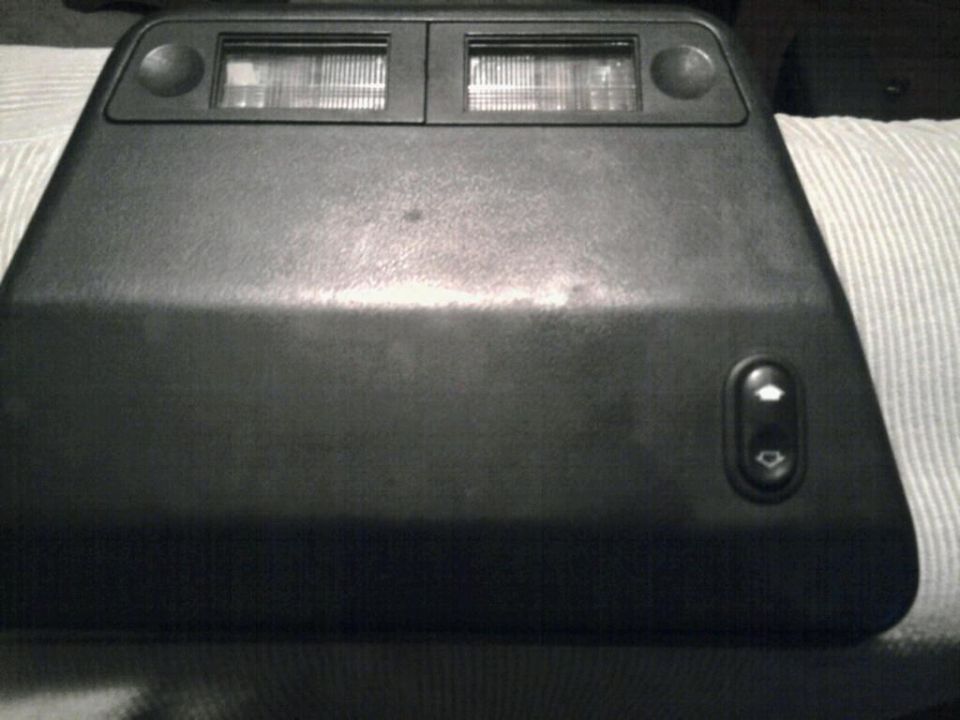 Black plastic overhead console with two rectangular lights and two circular buttons