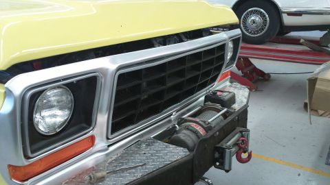 1978 Ford Bronco - Front view of a 1978 Ford Bronco, showing its grille and winch. Another car is in the background.