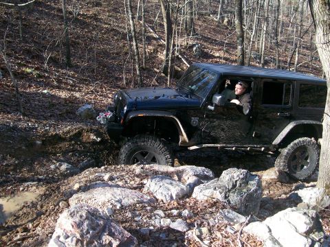 2007 Jeep Wrangler - A black 2007 Jeep Wrangler tackles a challenging off-road course with mud and rocks.
