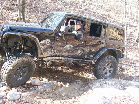 2007 Jeep Wrangler - This black 2007 Jeep Wrangler navigates a challenging off-road trail, its lifted suspension and tires.