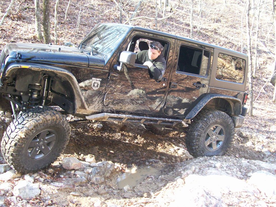 Black 2007 Jeep Wrangler off-roading with large tires and a lifted suspension