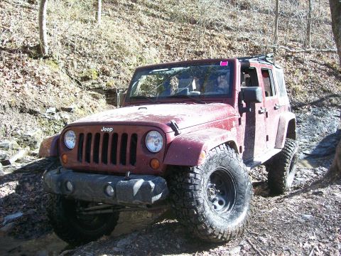 2007 Jeep Wrangler - A red 2007 Jeep Wrangler navigates a challenging off-road course, its capabilities.